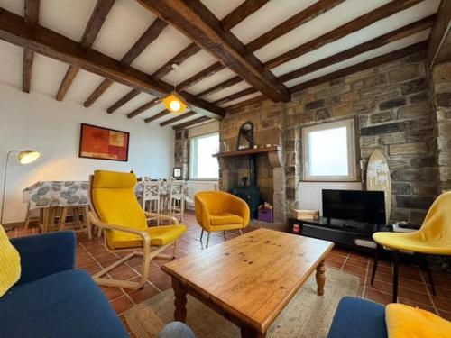 - un salon avec des chaises jaunes et une table en bois dans l'établissement Charmante maison bretonne proche de la mer, à Porspoder