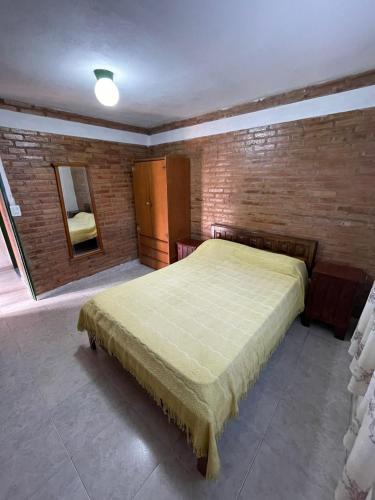 a bedroom with a bed and a brick wall at Cabaña petiza in Mina Clavero