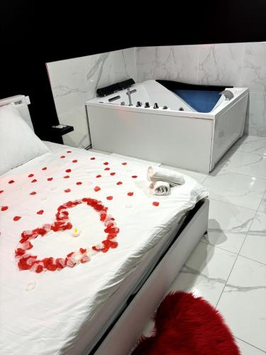 a white bed with red petals on it at My Suite II in Bourgoin