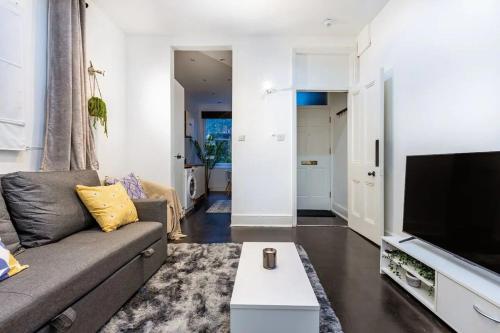 a living room with a couch and a flat screen tv at Cozy flat Near Paddington in London