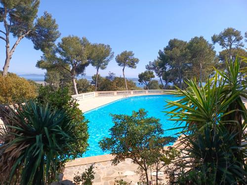 une grande piscine bleue avec des arbres en arrière-plan dans l'établissement Appartement 110 m2 vue mer environnement exceptionnel, à Hyères