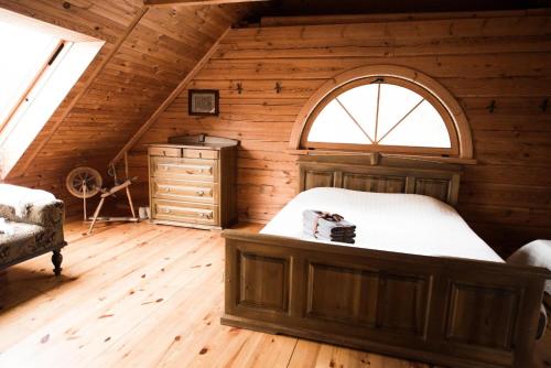 an attic bedroom with a bed and a window at Pakaso sodyba, šiaurinė pusė in Kirdeikiai