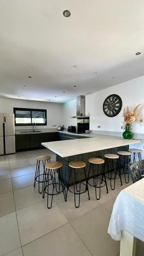 une cuisine avec un grand îlot et des tabourets de bar dans l'établissement CasaNota Haut de villa 200m2 avec piscine privée, à Porto-Vecchio