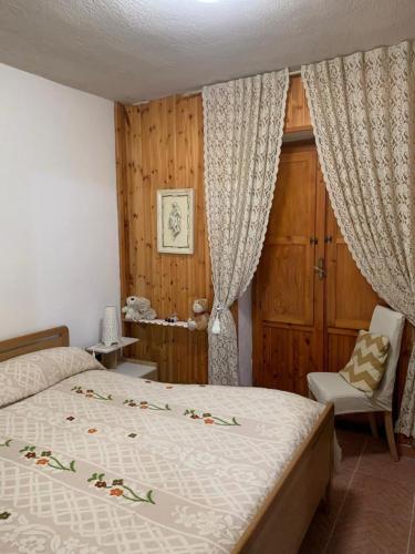 a bedroom with a bed and a chair and curtains at Sweet Home in Palena