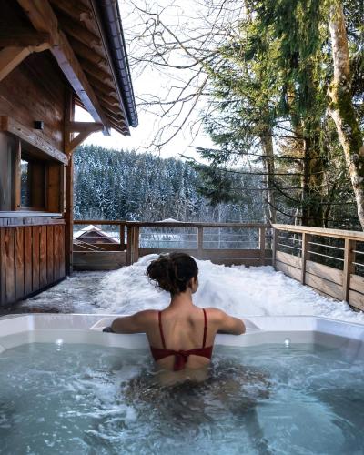 une femme dans un bain à remous dans la neige dans l'établissement Chalet Les Cimes - Sauna - Jacuzzi, à Gérardmer