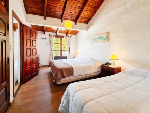 a bedroom with two beds and a wooden ceiling at Hotel Marqués del Lago in Villa Carlos Paz