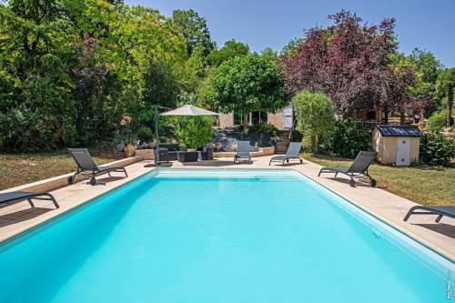 une grande piscine avec des chaises et un parasol dans l'établissement La Cabane du Trel Maison de Charme l Piscine, à Campagnac