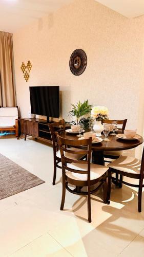 a dining room with a table with chairs and a television at Al Reem 1BR City View Pool Gym Family Biz Friendly Abu Dhabi in Mushayrib