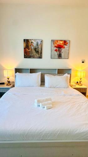 a white bed with two towels on top of it at Al Reem 1BR City View Pool Gym Family Biz Friendly Abu Dhabi in Mushayrib