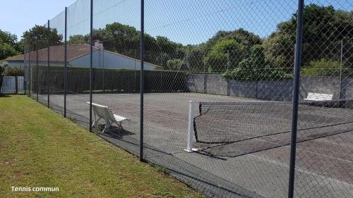 un court de tennis avec un banc sur une clôture dans l'établissement Superbe Logement à 200 m de la Plage ! T4 Coquillages, à Saint-Pierre-dʼOléron