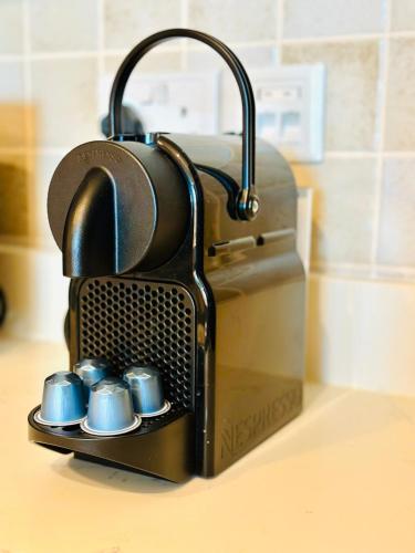a coffee maker on a counter with four blue cups at Al Reem 1BR City View Pool Gym Family Biz Friendly Abu Dhabi in Mushayrib