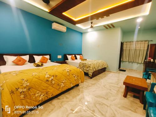 a bedroom with two beds and a blue wall at Dream Hampi Villa & Home Stay in Hampi