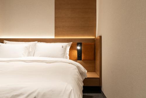a bedroom with a white bed with a wooden headboard at Garni Hotel Galeria in Banja Luka