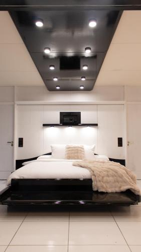 une chambre avec un grand lit blanc dans une pièce dans l'établissement Black & White Suite & SPA - Sauna & Jacuzzi, à Gif-sur-Yvette