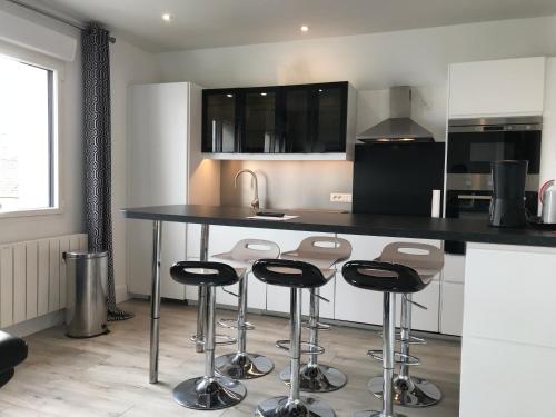 une cuisine avec un comptoir noir et des tabourets dans l'établissement appart 3 chambres terrasse, à Le Touquet-Paris-Plage