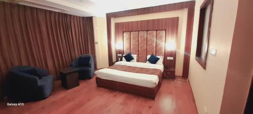 a hotel room with a bed and two chairs at Hotel Zoon Dabb Srinagar airport kashmir in Srinagar