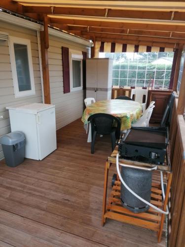 - une terrasse couverte avec une table et un grill dans l'établissement Mobil Home tout confort 6 a 8 personnes Aux Charmettes, aux Mathes