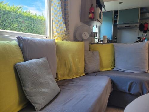 a living room with a couch with yellow and blue pillows at Mobil Home tout confort 6 a 8 personnes Aux Charmettes in Les Mathes