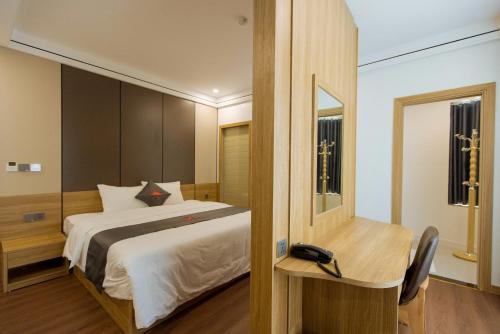 a bedroom with a bed and a desk and a mirror at Phương Đông Hotel Móng Cái in Móng Cái