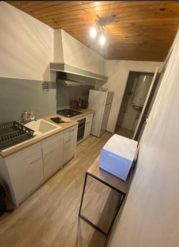 a kitchen with white cabinets and a blue box on a table at La Halte de Massiac 1er étage in Massiac