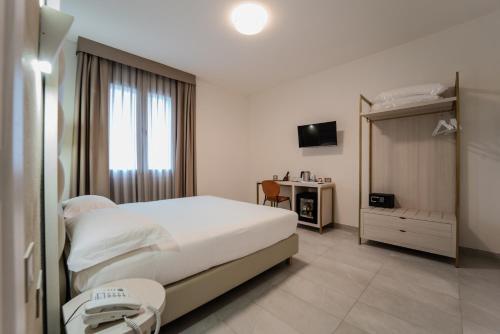 a bedroom with a bed and a desk and a television at Hotel Donatello in Modena