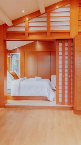 - une grande chambre avec un grand lit blanc et des murs en bois dans l'établissement Premium Spa Chalet - Sauna & Jacuzzi - 20min Paris, à Gif-sur-Yvette