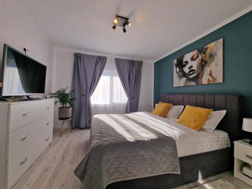 a bedroom with a bed with blue walls and a television at Elite Apartment Onesti in Onești