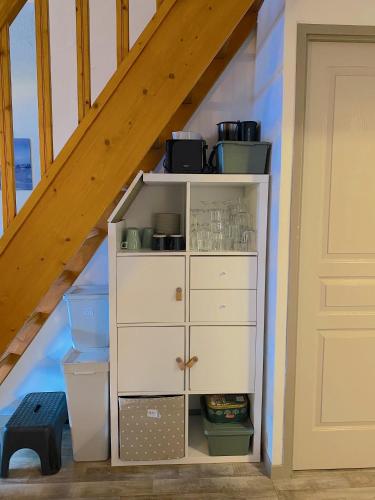 une armoire blanche dans une pièce située sous un escalier dans l'établissement L'Ourson skis aux pieds, à Valmeinier