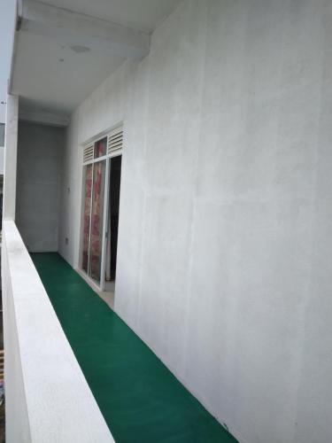 a room with a green floor and a white wall at SunRay Rest - Beach View Homestay in Mirissa
