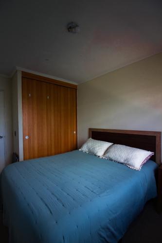 a bedroom with a large blue bed with a wooden headboard at Hermosa vista laguna tres Pascualas in Concepción