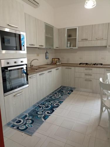 a kitchen with white cabinets and a rug on the floor at Appartamento Marco a pochi passi dal mare S.Vito in San Vito lo Capo
