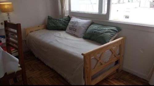 een slaapkamer met een houten bed met kussens en een raam bij Travel ART! in Mar del Plata