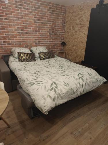 un grand lit dans une pièce avec un mur de briques dans l'établissement Studio indépendant neuf, à Saint-André-de-lʼEure