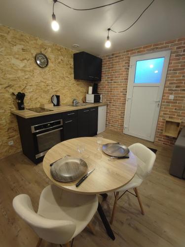 - une cuisine avec une table en bois et des chaises blanches dans l'établissement Studio indépendant neuf, à Saint-André-de-lʼEure