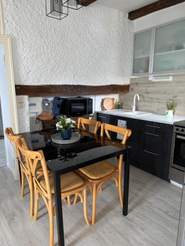 une cuisine avec une table noire et des chaises en bois dans l'établissement La Teranga, à Véreux