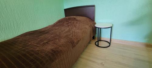 a bed with a brown blanket and a stool in a room at Hotel Maria in Mestia