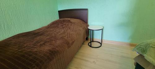 a bed with a brown blanket and two tables in a room at Hotel Maria in Mestia