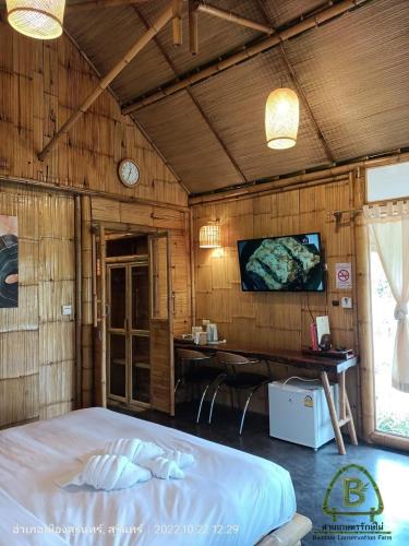 a bedroom with a bed and a desk and a tv at สวนเกษตรรักษ์ไผ่ Bamboo Conservation Farm in Surin