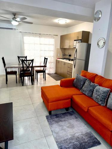 a living room with an orange couch and a kitchen at Casa Rivera Cancún in Cancún