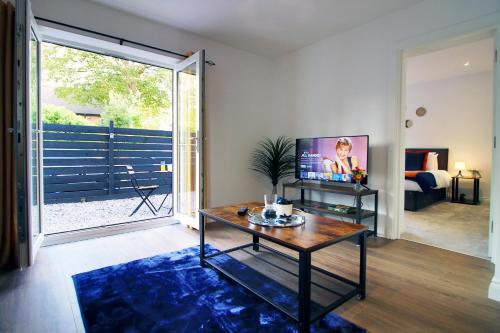 a living room with a tv and a table at Casa di pietra - Cardiff City centre apartment with patio, Free private parking in Cardiff