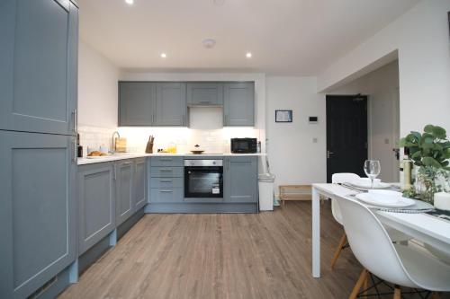 a kitchen with blue cabinets and a dining table at Casa di pietra - Cardiff City centre apartment with patio, Free private parking in Cardiff