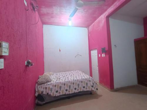 a room with a pink wall with a bed in it at Casa de reyes in Tizimín