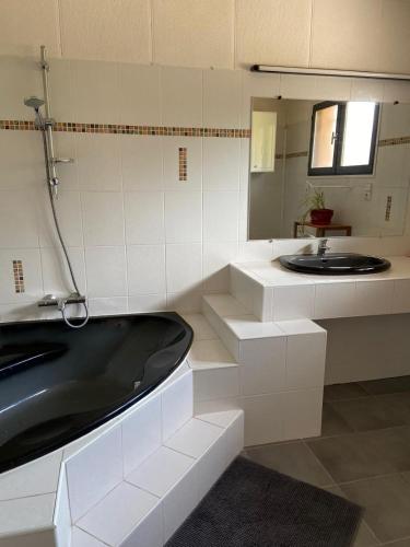 La salle de bains est pourvue d'une baignoire noire et d'un lavabo. dans l'établissement Villa Verano, à Villeneuve-lès-Bouloc