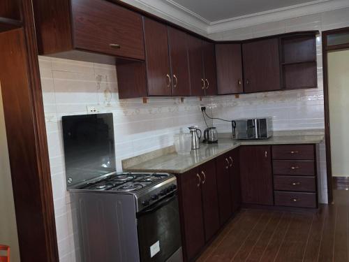 a kitchen with wooden cabinets and a stove top oven at Akright Villa in Buzzi