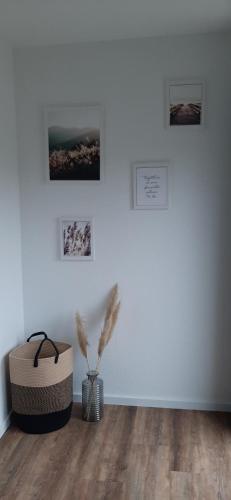 a room with a white wall with a vase and pictures at Servus & Moin - Bei uns Daheim! in Meißendorf