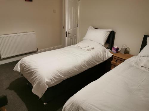 a bedroom with two beds and a table with a night stand at Family Friendly I Pets Welcome I Short Walk to Railway Station I 10min Drive to Safari Park in Kidderminster