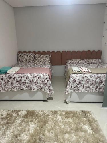 a bedroom with two beds and two rugs at Casa 108 in Guaibim