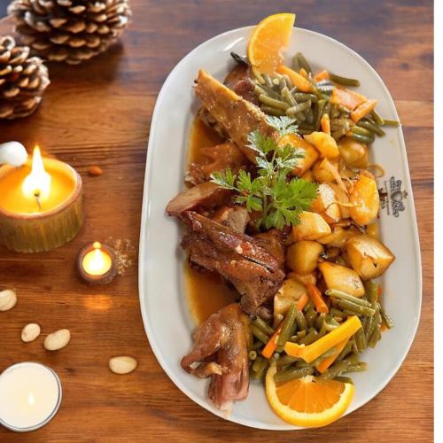 a plate of food with meat and vegetables and a candle at Residencial A Cista in Vila da Ponte