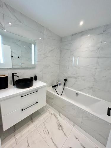 une salle de bain blanche avec une baignoire et un lavabo dans l'établissement Le Grand Soleil, à Nice