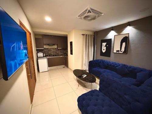 a living room with blue couches and a tv at Luxury condo with rooftop pool! in Islamabad